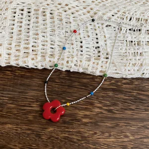 Macro detail of the vibrant red flower pendant and colorful beads on a silver necklace chain