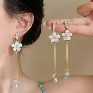 Close-up of French style floral tassel earrings with white enamel and crystals