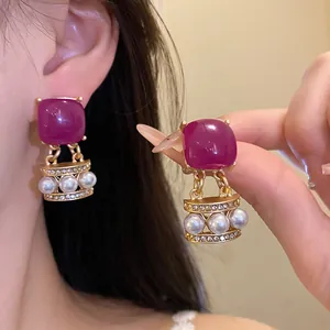 Detailansicht von Vintage-Ohrringen mit lila Steinen und eleganten Perlenanhängern