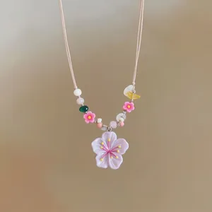 Bohemian style colorful beaded necklace featuring a large resin cherry blossom pendant