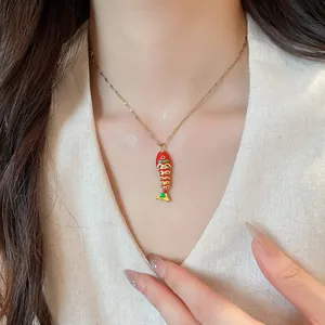 Detailed macro view of a vibrant enamel fish pendant necklace worn on a woman's neck