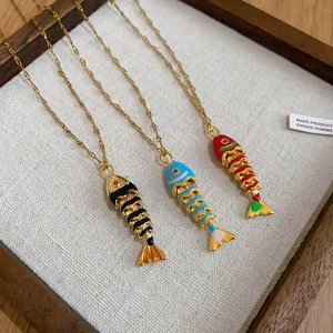 Close-up of three colorful fish bone pendant necklaces with intricate gold plating.