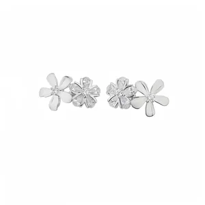 Élégantes boucles d'oreilles fleurs en argent avec zircons étincelants sur fond blanc.