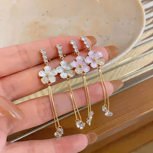 Close-up of elegant flower tassel earrings with drip oil petals and gold chains.