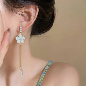 Close-up of elegant French style white flower tassel drop earrings on model's ear