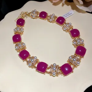Detailansicht einer Vintage-Goldkette mit magentafarbenen Steinen, Perlen und Strass