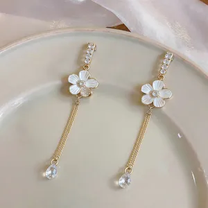 Macro detail of French luxury floral earrings featuring gold tassels and crystal drops