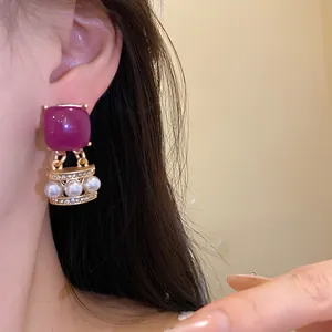 Nahaufnahme eines Vintage-Ohrrings mit lila Stein und Perlen an einem Modell
