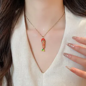 Close-up of a colorful enamel fish pendant necklace on a delicate gold chain