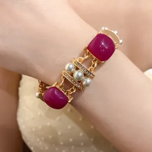 Makroansicht eines goldenen Armbands im Vintage-Stil mit magentafarbenen Steinen