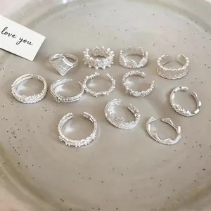 Detailed macro view of eleven different silver-colored lace star and crown rings on a plate