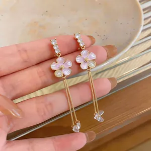 Close-up of elegant pink enamel flower drop earrings with long gold chain tassels