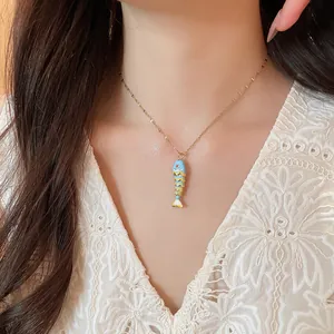 Detailed view of a creative colorful fish pendant necklace on a fine gold clavicle chain