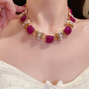 Nahaufnahme einer goldenen Vintage-Halskette mit lila Steinen und Perlen am Modell