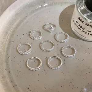 Detail view of silver French lace and star rings set on a textured decorative plate.