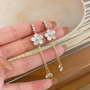 Close-up of elegant French style white flower earrings with long gold tassels