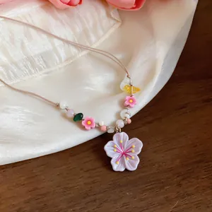 Detailed close-up of a handmade beaded necklace with a pink resin cherry blossom pendant