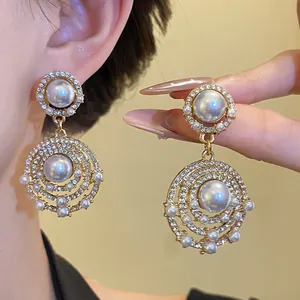 Detailansicht von Vintage-Goldohrringen mit eleganten Perlen und funkelnden Strasssteinen.