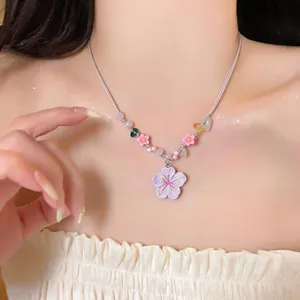Macro view of a summer style beaded necklace with resin flower pendant on model.