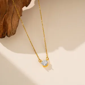 Primer plano de collar de acero de titanio dorado con colgante de circón redondo