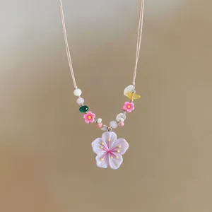 Close-up of handmade cherry blossom resin pendant necklace with colorful glass beads.