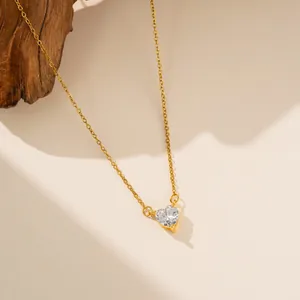 Detalle de un collar de acero de titanio dorado con un colgante de circón de corazón