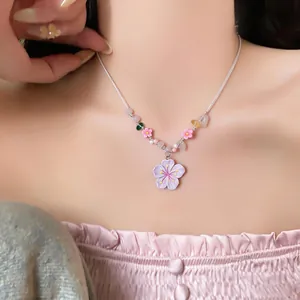 Detail view of a floral beaded necklace with resin flower pendant worn by a model.