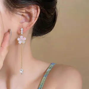 Close-up of elegant pink flower tassel earrings worn by a model in a luxury detail shot.