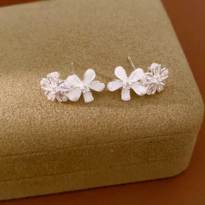 Élégantes boucles d'oreilles fleurs en résine et zircons sur un bel écrin doux.