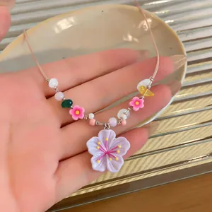 Macro detail of a colorful beaded necklace featuring a resin cherry blossom pendant.