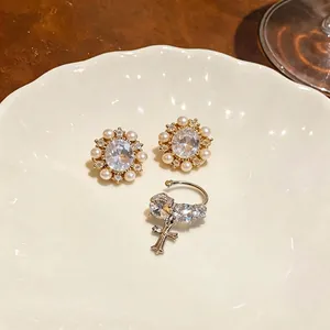 Vintage 14k gold plated pearl and zircon earrings with cross charm on a plate