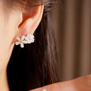 Boucles d'oreilles élégantes en zircon et fleurs en résine blanche sur l'oreille