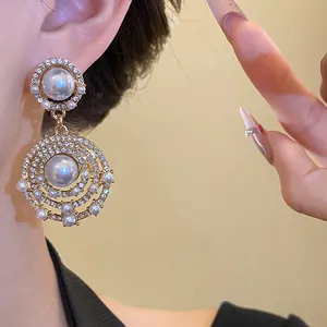 Detailaufnahme von Vintage-Goldohrringen mit Perlen und schimmernden Strasssteinen