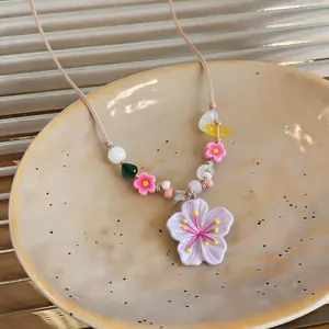 Detailed view of resin flower pendant and colorful glass beads on a summer necklace