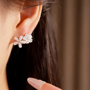 Vue détaillée de boucles d'oreilles fleurs en résine et zircon portées sur l'oreille