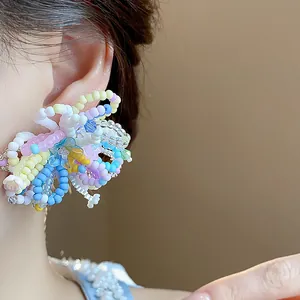 Close-up view of a vibrant dopamine-style multi-colored beaded flower earring on a model