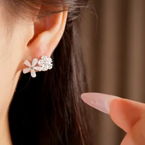 Gros plan détaillé montrant des boucles d'oreilles fleur en zircon et résine sur l'oreille