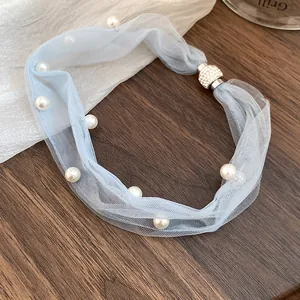 Detail of light blue mesh necklace with pearls and rhinestone magnetic clasp.