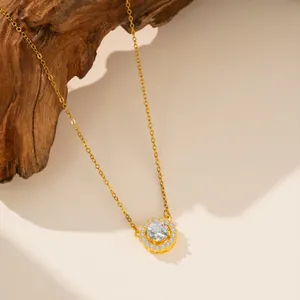 Primer plano de un collar de acero de titanio dorado con un colgante redondo de circón