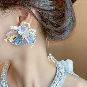 Detailed view of colorful dopamine beaded glass flower stud earrings on a model's ear