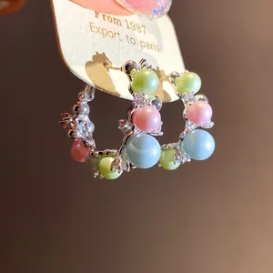 Detailed macro view of silver hoop earrings featuring pastel beads and cubic zirconia