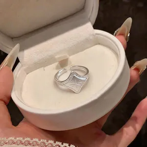 Close-up of a silver star-engraved signet ring inside a white round jewelry gift box