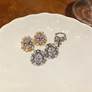 Macro view of 14k gold plated zircon and pearl earrings with French retro style