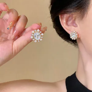 Elegant vintage stud earrings with central oval zircon and surrounding pearls on ear