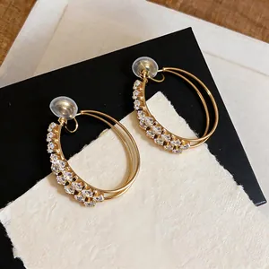 Close-up of elegant double-layered gold hoop clip-on earrings with sparkly zircons.