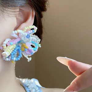 Close-up view of a colorful dopamine beaded flower earring on an Asian model's ear.