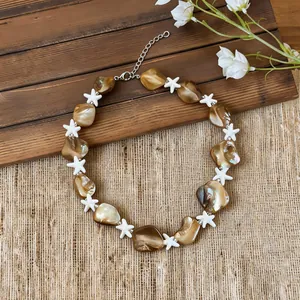 Close-up detail of brown shell and white starfish beaded necklace for beach vacation style.