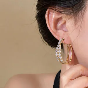 Close-up of elegant double-layered gold hoop earrings with sparkling zircon stones
