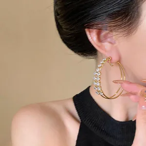Close-up of elegant double-layered gold hoop clip-on earrings with sparkling clear zircons.