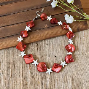 Detailed view of red shell beads and white starfish charms on a vacation necklace.
